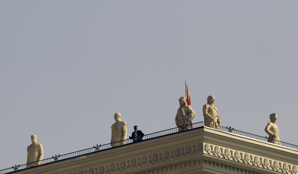 In this Oct. 23, 2012 photo a police officer stands on a rooftop alongside numerous sculptures positioned atop the new Ministry of Foreign Affairs building in downtown Skopje, Macedonia. Grandiose buildings, monuments, fountains and bridges are dotting the city center as part of a government project called Skopje 2014, officially intended to rebuild a city that lost many of its landmarks in a 1963 earthquake. (AP Photo/Darko Vojinovic)