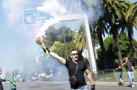 A striking taxi driver holds a flare on the Promenade des Anglais during a demonstration as part of a national protest against car-sharing service Uber in Nice, France, June 25, 2015. (REUTERS/Jean-Pierre Amet)