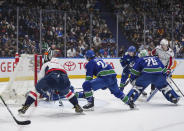 Washington Capitals' Alex Ovechkin, front left, scores as Vancouver Canucks' Pius Suter (24), goalie Casey DeSmith (29), Quinn Hughes (43) and Washington's Connor McMichael, back right, watch during the second period of an NHL hockey game in Vancouver, British Columbia, Saturday, March 16, 2024. (Darryl Dyck/The Canadian Press via AP)