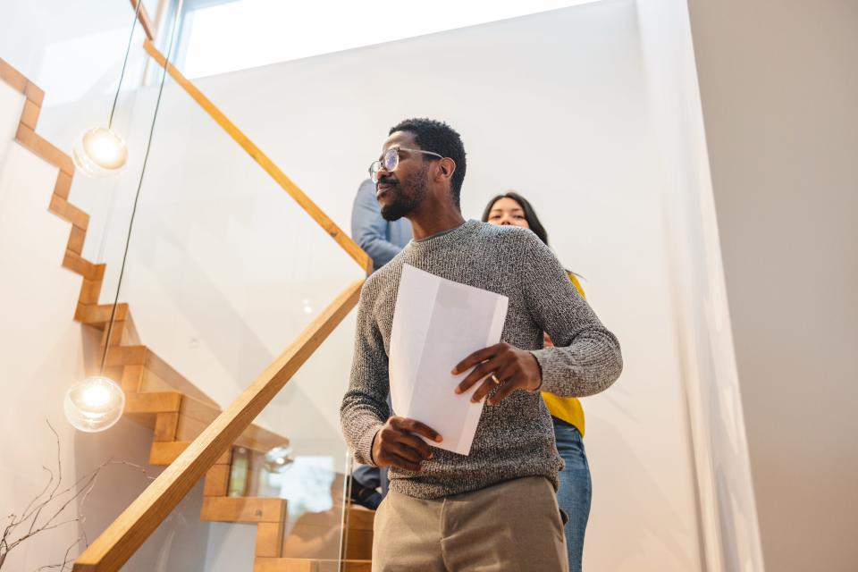 <h1 class="title">Diverse Couple Walking Down The Stairs Of The Beautiful Modern Apartment With An Adult Caucasian Male Real Estate Agent Who Is Showing Them The Place</h1><cite class="credit">Photo: Getty Images</cite>