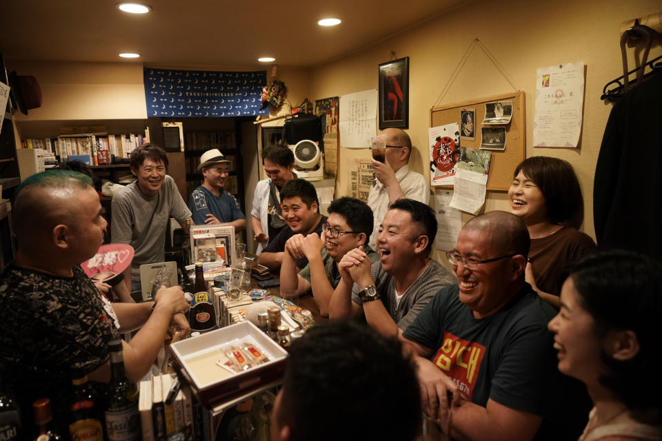 A group of patrons laugh as they listen to entertainer Tadashi Yokoda, far left, in a bar at the Golden Gai in the Shinjuku district of Tokyo, July 28, 2019. (AP Photo/Jae C. Hong)