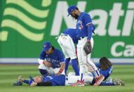 Toronto Blue Jays cener fielder George Springer, bottom, lies on the field as teammates try to help him after he collided with Bo Bichette while trying to catch a short fly ball during the eighth inning of Game 2 of a baseball AL wild-card playoff series against the Seattle Mariners, Saturday, Oct. 8, 2022, in Toronto. (Frank Gunn/The Canadian Press via AP)