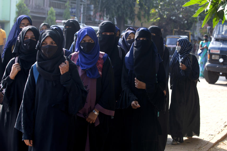 Indian girl students who were barred from entering their classrooms for wearing hijab, a headscarf used by Muslim women, walk outside their college in Udupi, India, Monday, Feb. 7, 2022. Muslim girls wearing hijab are being barred from attending classes at some schools in the southern Indian state of Karnataka, triggering weeks of protests by students. (AP Photo)