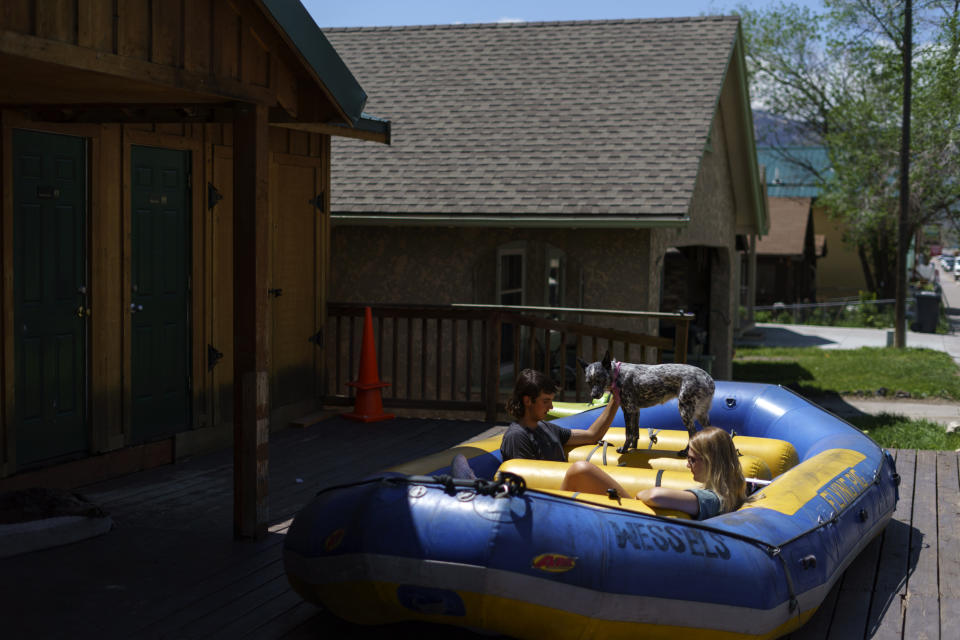 Jackson Muller, left, and Christie Davis, sit in a raft with Bonnie, the owners dog of Flying Pig Adventures, a rafting and adventure company along the Yellowstone River, in Gardiner, Mont., Wednesday, June 15, 2022. Historic floodwaters have closed Yellowstone National Park impacting the local economy which relies heavily on tourism. (AP Photo/David Goldman)