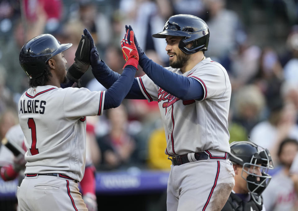 Atlanta Braves' Ozzie Albies, left, congratulates Travis d'Arnaud for his two-run home run off Colorado Rockies starting pitcher Austin Gomber during the third inning of a baseball game Thursday, June 2, 2022, in Denver. (AP Photo/David Zalubowski)