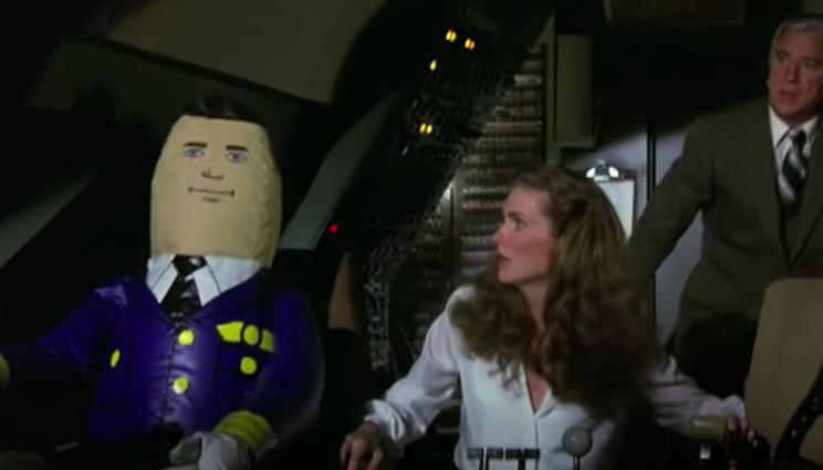 A woman looks horrified at a blow-up doll posing as a pilot