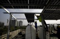 Workers of Solar Square put up a panel on the rooftop of a residence in Gurugram on the outskirts of New Delhi, India, Tuesday, Feb. 20, 2024. India is renewing its push to add rooftop solar to meet the needs of a fast-growing nation that's hungry for energy. (AP Photo/Manish Swarup)