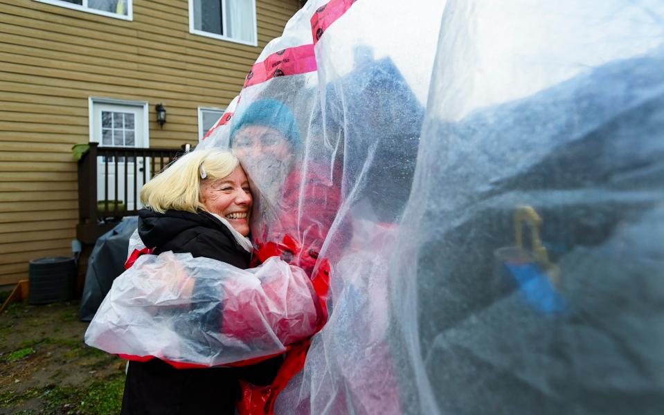 Carolyn Ellis, left, creator of the hug glove hugs her mother Susan Watts, 74, in her backyard - Nathan Denette/The Canadian Press