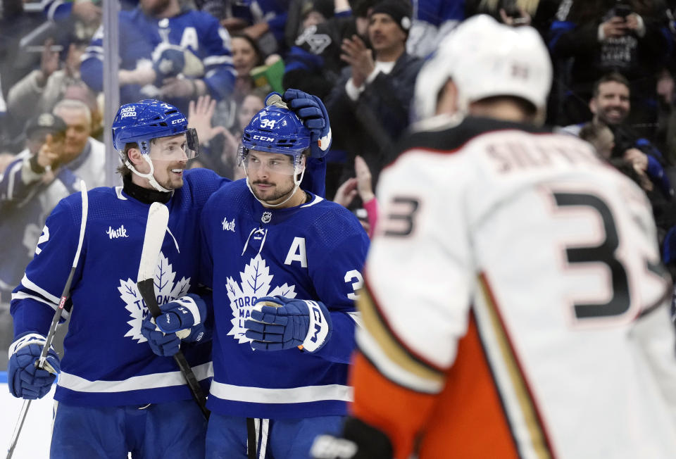 Toronto Maple Leafs' Auston Matthews, center, is congratulated by Simon Benoit after scoring his third goal against the Anaheim Ducksduring the second period of an NHL hockey game, Saturday, Feb. 17, 2024 in Toronto. (Chris Young/The Canadian Press via AP)