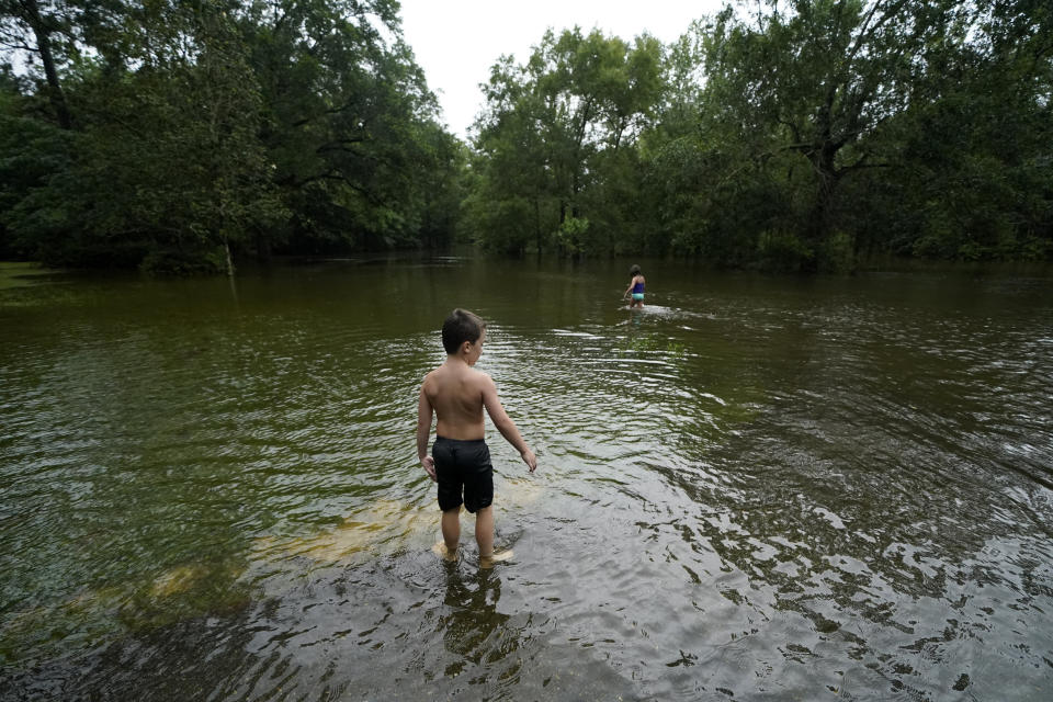 Marina Kingsmill and her brother Raylan play in the flooded street in front of their home after Tropical Storm Claudette passed through in Slidell, La., Saturday, June 19, 2021. The National Hurricane Center declared Claudette organized enough to qualify as a named storm early Saturday, well after the storm's center of circulation had come ashore southwest of New Orleans. (AP Photo/Gerald Herbert)