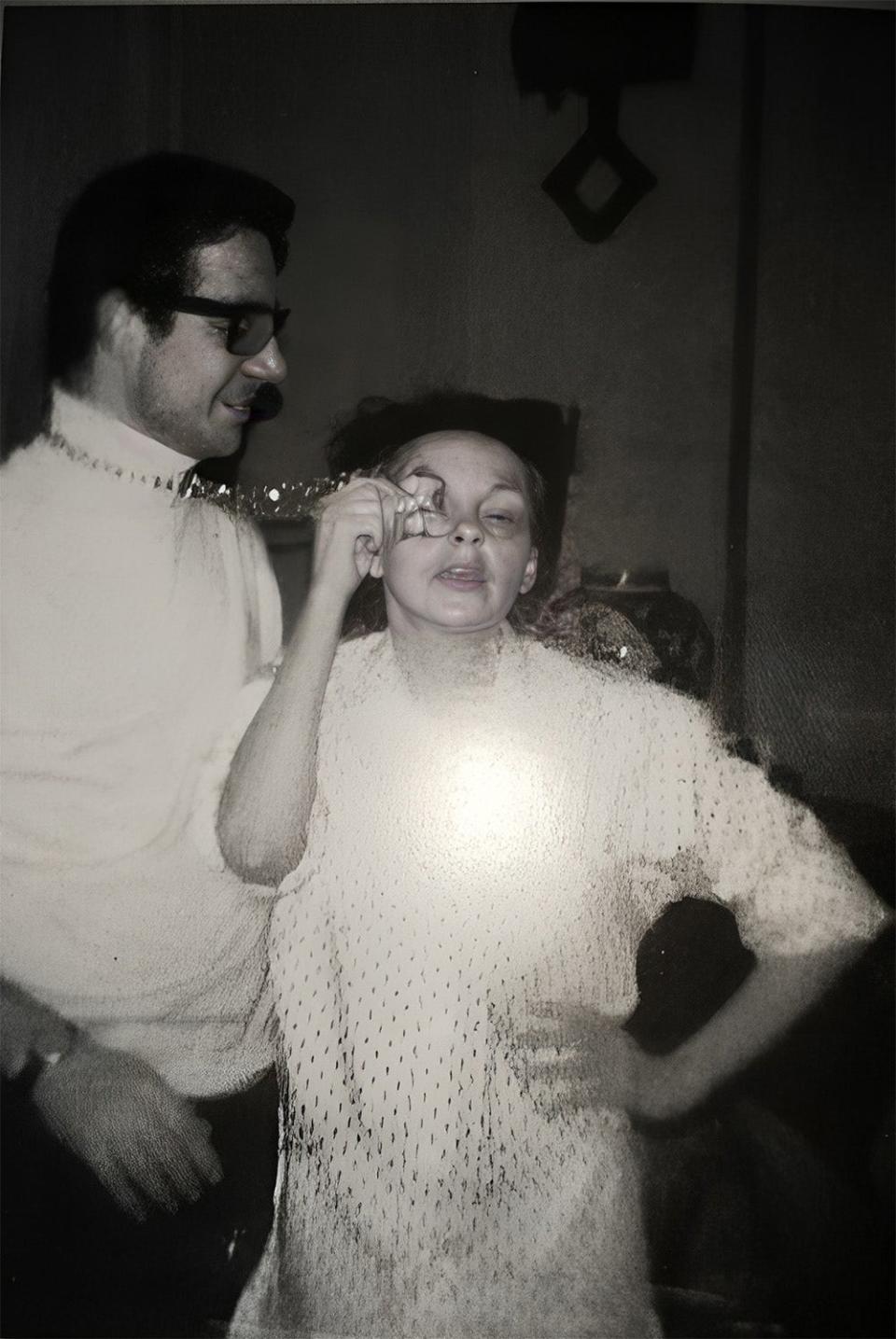 John Meyer standing next to Judy Garland as she applies her eye makeup