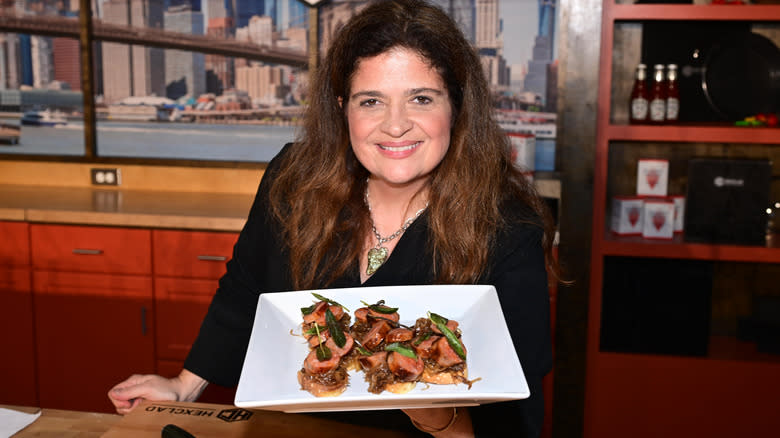 Alex Guarnaschelli smiles holding a plate of food