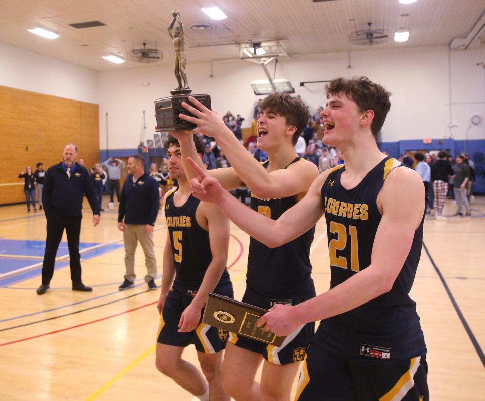 Lourdes' captains, from left, Hall Schofield, Jon Selander and Patrick Faughnan carry the MHAL trophy and plaque after winning the boys basketball final against Spackenkill on February 23, 2023. 