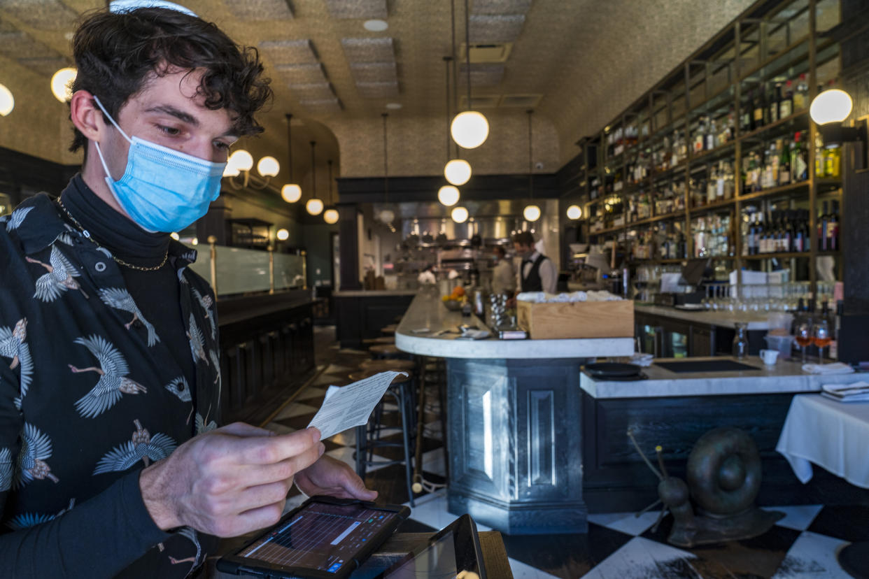 Restaurant host Joey Tyler verifies a patron's vaccination card at French restaurant Petit Trois in Los Angeles on Friday, Nov. 5, 2021. (AP Photo/Damian Dovarganes)