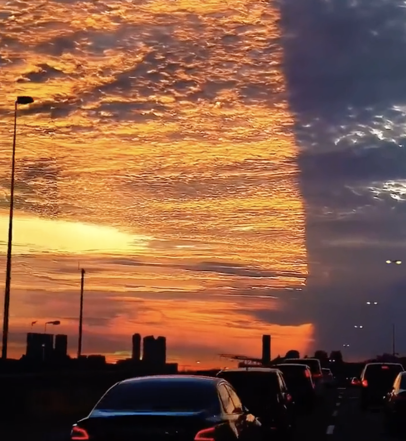 A sky above a highway showing red clouds on one side and a dark sky on the other