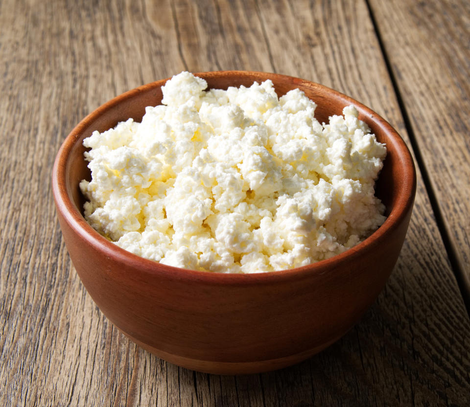 Brown wooden Bowl of homemade curd on a dark brown wooden background, side view, close up