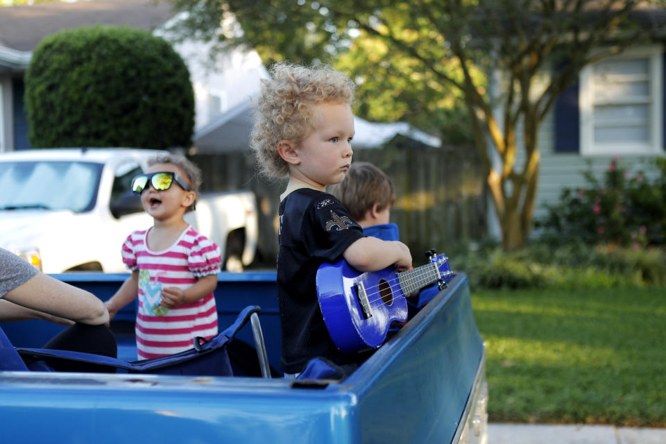 Walter D'Arensbourg, 3, plays with his toy guitar as Adam Pearce performs a concert from his front porch in Jefferson Parish, La., a suburb of New Orleans, Wednesday, April 29, 2020. (AP Photo/Gerald Herbert)