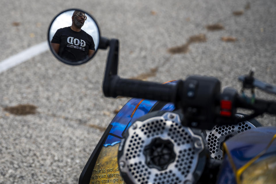 Yusuf Jackson is seen reflected in a motorcycle mirror wearing a shirt reading "God is in Control" during a "Black Bikers Vote," rally Saturday, Nov. 5, 2022, in Philadelphia. (AP Photo/Joe Lamberti)