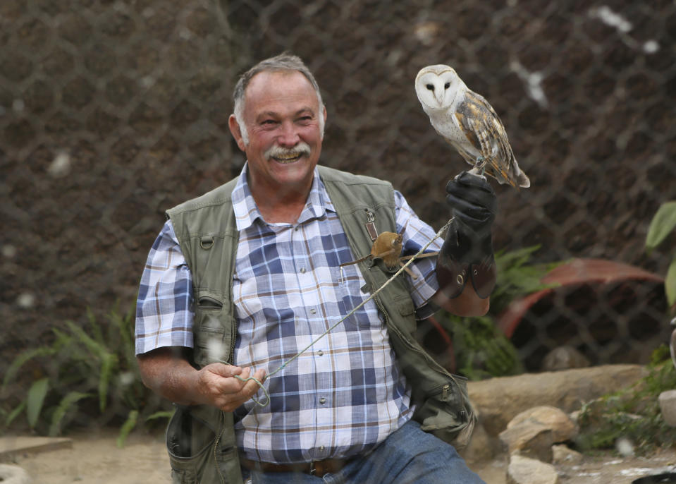 Gary Strafford, a Zimbabwean falconer, holds an owl inside one of the cages at his bird sanctuary, Kuimba Shiri, near Harare, Zimbabwe, Wednesday, June, 17, 2020. Kuimba Shiri, Zimbabwe's only bird park, has survived tumultuous times, including violent land invasions and a devastating economic collapse. Now the outbreak of COVID-19 is proving a stern test. With Zimbabwe’s inflation currently at more than 750%, tourism establishments are battling a vicious economic downturn worsened by the new coronavirus travel restrictions. (AP Photo/Tsvangirayi Mukwazhi)