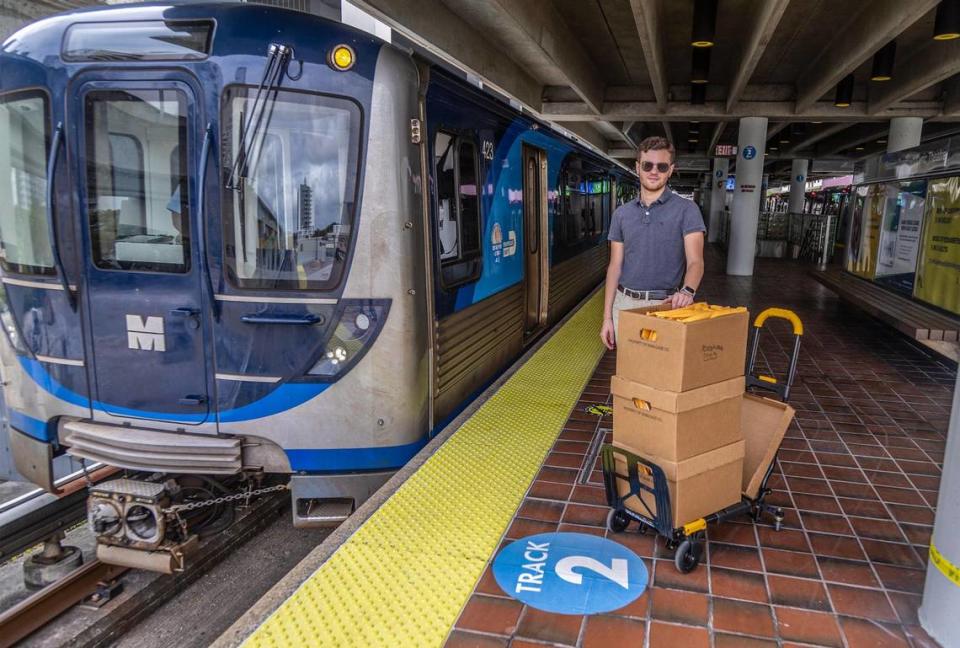 El activista del transporte público Kevin Amézaga posa en la plataforma de la estación de Metrorail de Overtown con cajas llenas de registros públicos del Metrorail que obtuvo del Condado Miami-Dade mientras intenta descubrir porqué Metrorail puede llegar tan tarde a veces, en Miami, el viernes 27 de octubre de 2023.