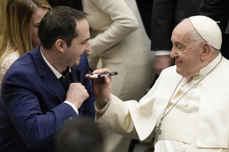 Pope Francis autographs the suit of a newly wed groom during his weekly general audience in the Pope Paul VI hall at the Vatican, Wednesday, Dec. 20, 2023. (AP Photo/Andrew Medichini)