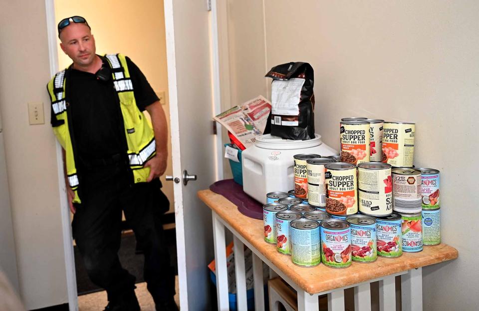 Milford Animal Control Officer Keith Haynes with cans of dog food at Milford Animal Control, Sept. 21, 2022. The department recently announced a shortage of food.