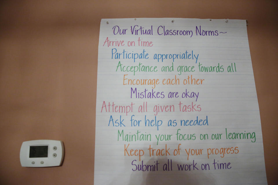 A list of virtual classroom norms hangs on Aimee Rodriguez Webbwall in her virtual classroom for a Cobb County school, on Tuesday, July 28, 2020, in Marietta, Ga. After a rocky transition to distance learning last spring, Webb is determined to do better this fall. She bought a dry-erase board and a special camera to display worksheets, and she set up her dining room to broadcast school lessons. (AP Photo/Brynn Anderson)