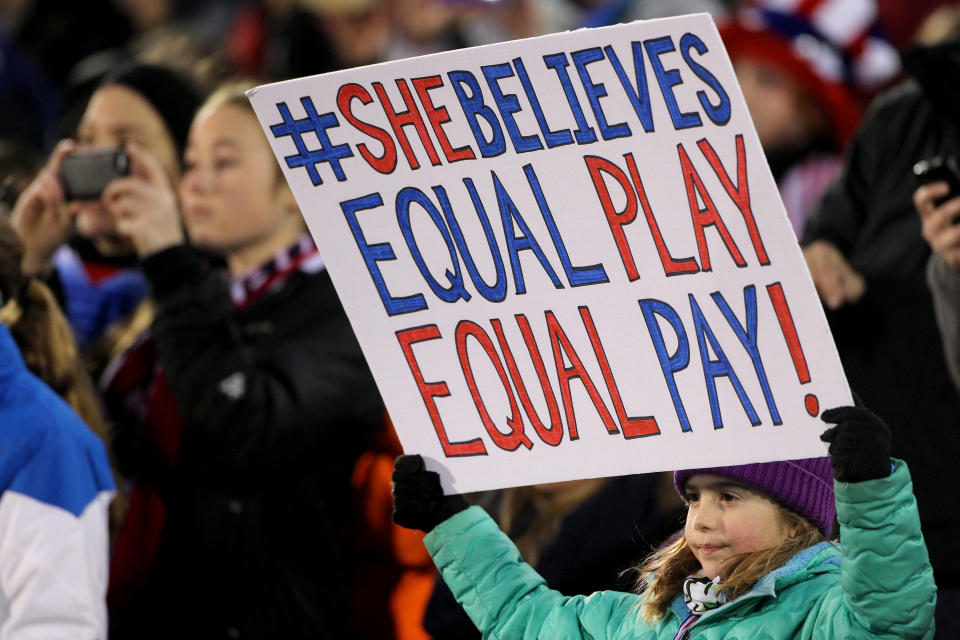 A young fan holds an "equal pay" banner during a USWNT friendly against Colombia in 2016. (Photo Tim Clayton/Corbis via Getty Images)