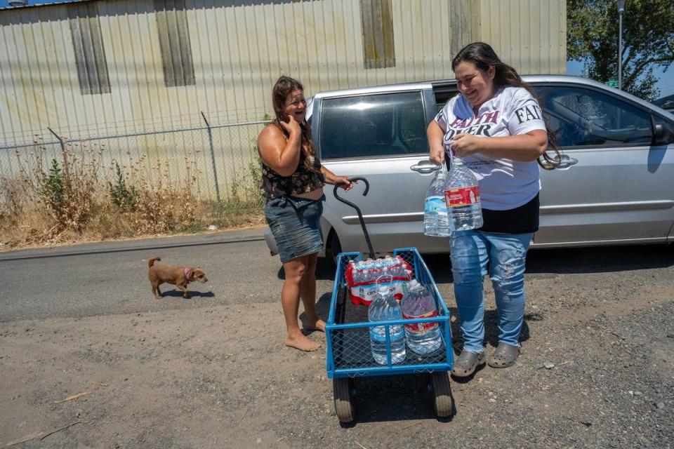 Crystal Sanchez, founder and president of the Sacramento Homeless Union a local chapter of the National Homeless Union, passes out water to Dawn Wainscott, 43, on July 7. Wainscott came with three little dogs. Water deliveries have resumed at Camp Resolution in North Sacramento, but 33 other camps are without water.