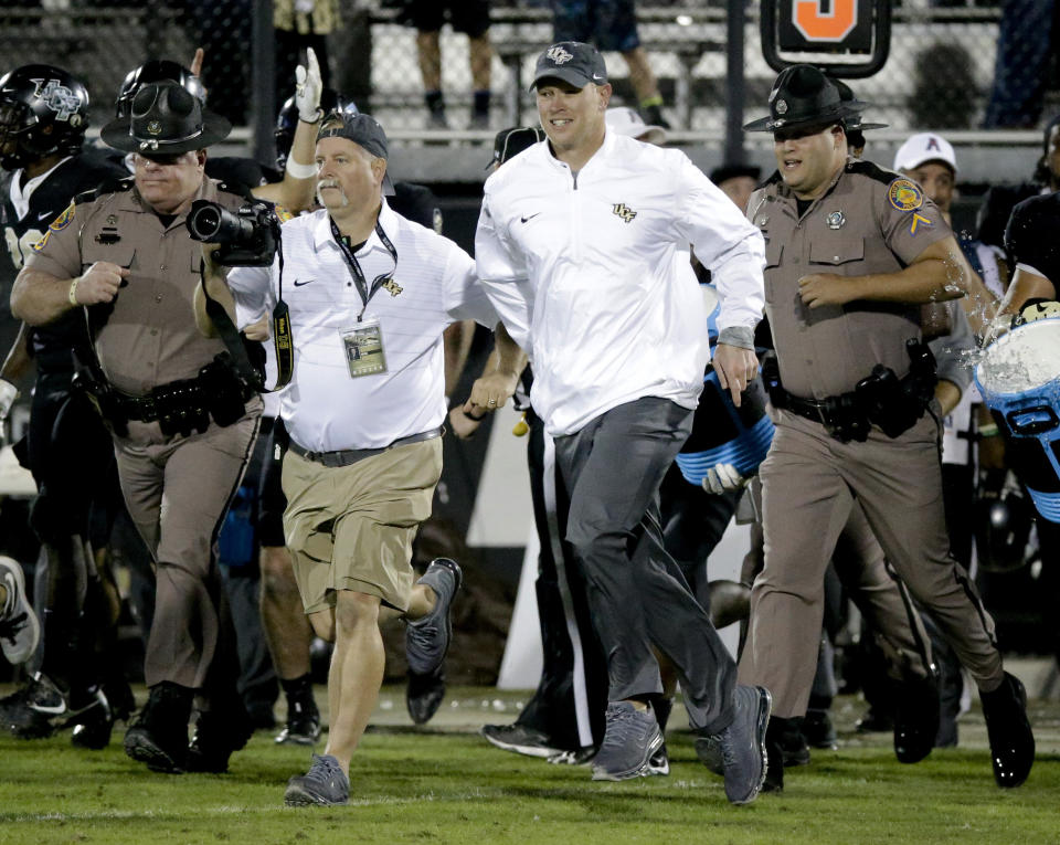 Central Florida coach Scott Frost (C) runs onto the field after the team defeated South Florida 49-42 in an NCAA college football game, Friday, Nov. 24, 2017, in Orlando, Fla. (AP Photo/John Raoux)