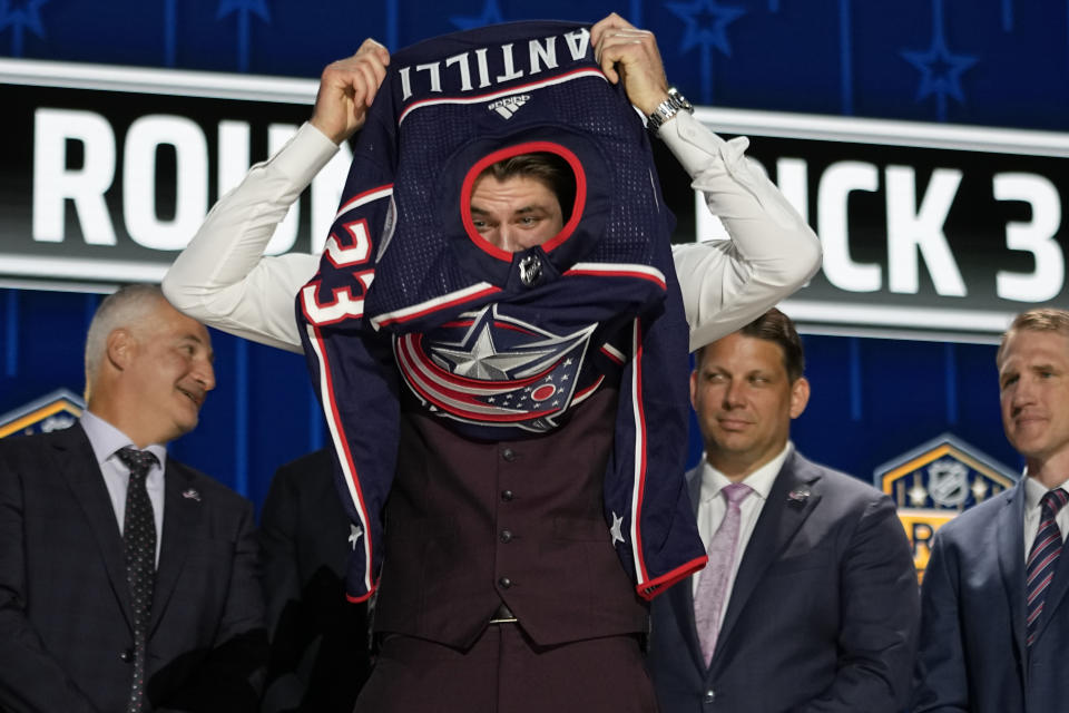 Adam Fantilli puts on a Columbus Blue Jackets jersey after being picked by the team during the first round of the NHL hockey draft Wednesday, June 28, 2023, in Nashville, Tenn. (AP Photo/George Walker IV)