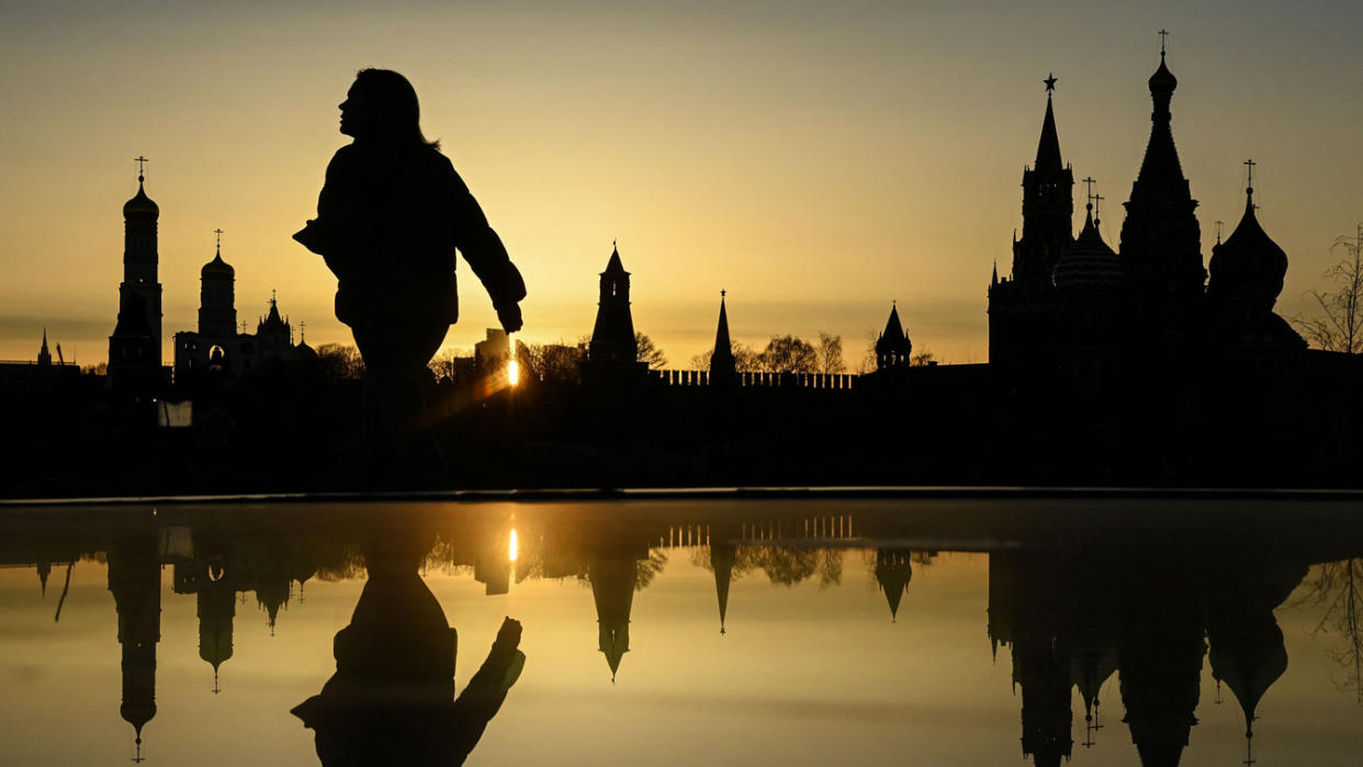 A silhouette of a person walking in front of the Moscow skyline.