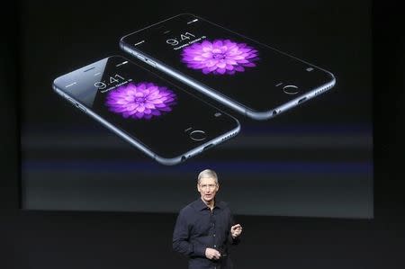 Apple CEO Tim Cook stands in front of a screen displaying the IPhone 6 during a presentation at Apple headquarters in Cupertino, California October 16, 2014. REUTERS/Robert Galbraith
