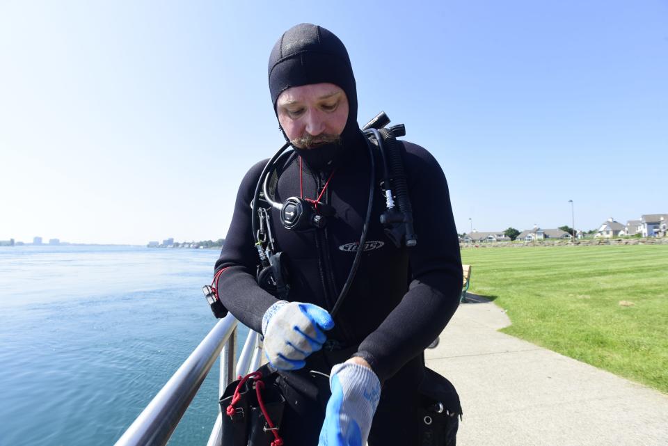 Tim Massey, a Shelby Township resident, puts on scuba-diving gear before jumping in the St. Clair River off the boardwalk at the Thomas Edison Parkway in Port Huron on Wednesday, June 15, 2022. Massey said that he loves coming to Port Huron to scuba dive to see sturgeon.