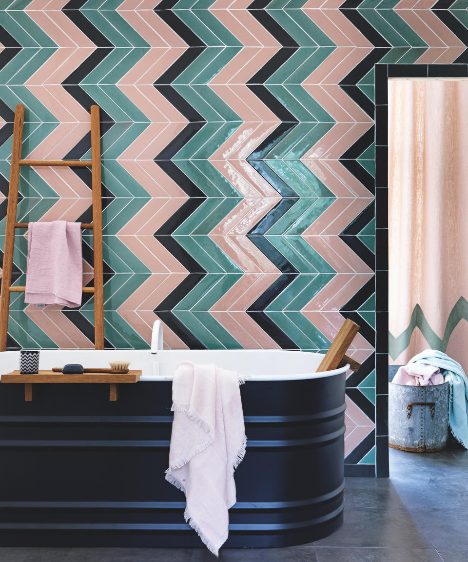 Bathroom with a black bath in front of pink and green chevron tiles