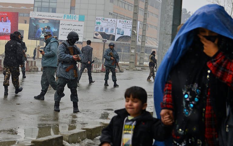 An Afghan woman with her child (right) move to safety as security personnel secure the site of a suicide attack near the Afghan intelligence agency headquarters in Kabul on January 16, 2013. A squad of suicide bombers attacked the intelligence agency headquarters in heavily-fortified central Kabul Wednesday, killing at least one guard and wounding dozens of civilians, officials said