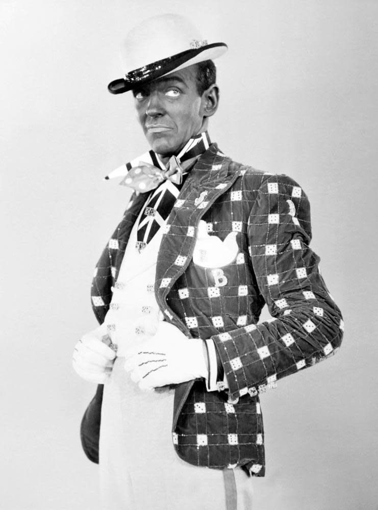 Fred Astaire, in blackface, wearing a hat, scarf, gloves and square-patterned velvet jacket in Swing Time (1936)