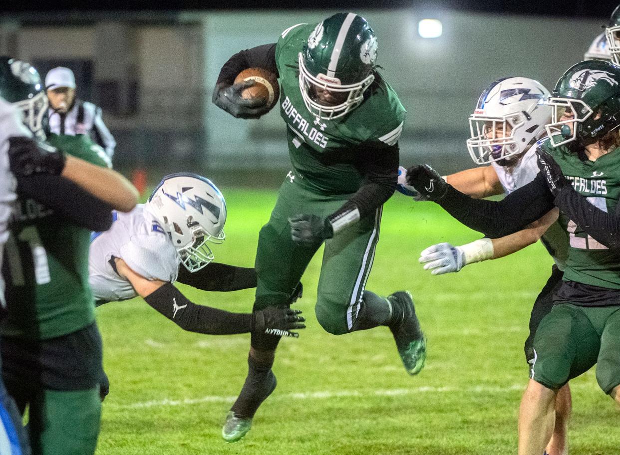 Manteca's Bryson Davis, center, tires to leap past Rocklin's Eli Hardy, left, and Derek Houston during a Sac-Joaquin Section Division II playoff game at Manteca's Guss Schmiedt Stadium.