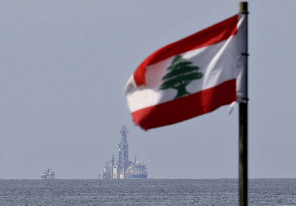 A Lebanese flag flutters in the wind as the drilling ship Tungsten Explorer is seen off the coast of Beirut, Lebanon, Thursday, Feb. 27, 2020. Lebanon's president on Thursday inaugurated Lebanon's first offshore exploratory drilling for oil and gas, calling it a "historic day" for the cash-strapped country. (AP Photo/Hussein Malla)