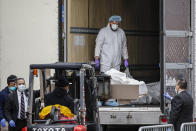 A body wrapped in plastic is loaded onto a refrigerated container truck used as a temporary morgue by medical workers wearing personal protective equipment due to COVID-19 concerns, Tuesday, March 31, 2020, at Brooklyn Hospital Center in the Brooklyn borough of New York. The new coronavirus causes mild or moderate symptoms for most people, but for some, especially older adults and people with existing health problems, it can cause more severe illness or death. (AP Photo/John Minchillo)