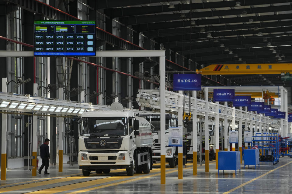 A worker walks by liquid tanker trucks at a Yizhuan Automobile Co. manufacturing factory during a media-organized tour in Shiyan city in central China's Hubei Province on May 12, 2023. China's manufacturing and consumer spending are weakening after a strong start to 2023 after anti-virus controls ended. (AP Photo/Andy Wong)