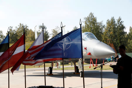 NATO (R to L), U.S., Poland's and Latvia's flags flutter in front of U.S. Air Force F-15C Eagle fighter during NATO Baltic air policing mission takeover ceremony in Siauliai, Lithuania August 30, 2017. REUTERS/Ints Kalnins