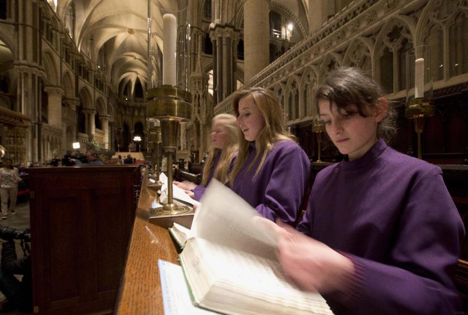 In this Wednesday, Jan. 22, 2014 photo, Choristers Chloe Chawner, right, Poppy Braddy, centre, and Abby Cox look at their hymn books at Canterbury Cathedral, Canterbury, England, as the first all female choir at the cathedral rehearses prior to their debut on Jan. 25. The pure, high voices of the choir soar toward the vaulted ceiling of Canterbury Cathedral as they have for more than 1,000 years. Just one thing is different _ these young choristers in their purple cassocks are girls, and their public debut at Evensong on Saturday will end centuries of all-male tradition.Canterbury is not the first British cathedral to set up a girls' choir, but as mother church of the 80 million-strong Anglican Communion _ one struggling with the role of women in its ranks _ its move has special resonance. (AP Photo/Alastair Grant)