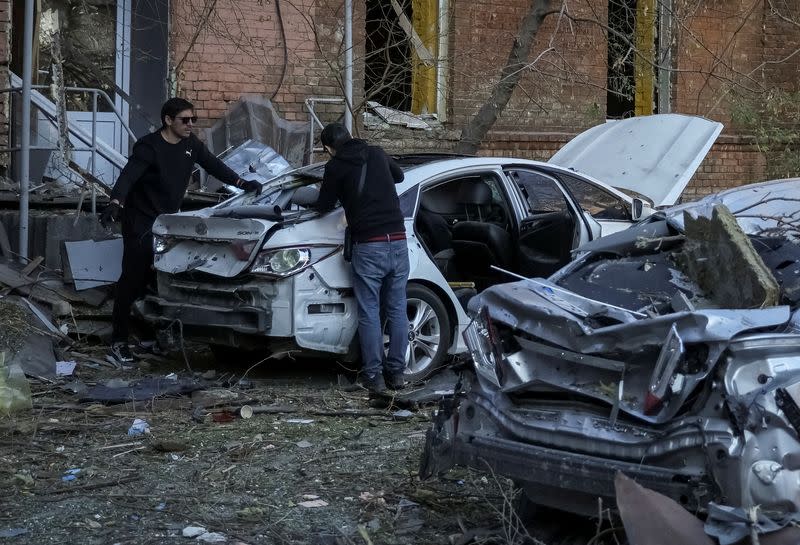 Local residents check their car, destroyed by the previous day's Russian military strike, as Russia's attack on Ukraine continues, in central Kyiv