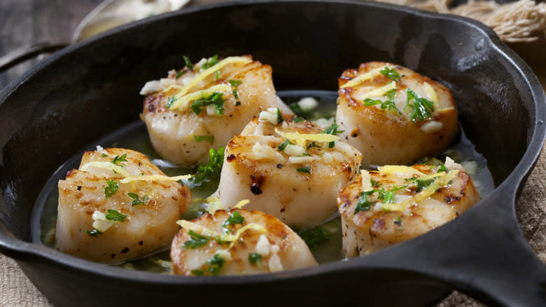 Cooked scallops in pan with herbs