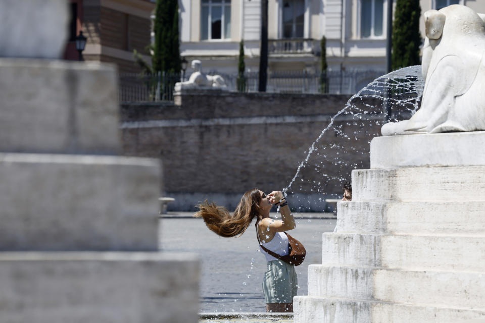 A woman shakes out her hair by a fountain in Piazza del Popolo Square in downtown Rome, Thursday, July 11, 2024. (Cecilia Fabiano/LaPresse via AP)