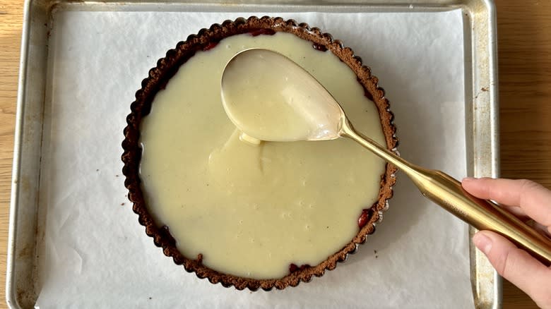 spreading white chocolate ganache on cranberry tart