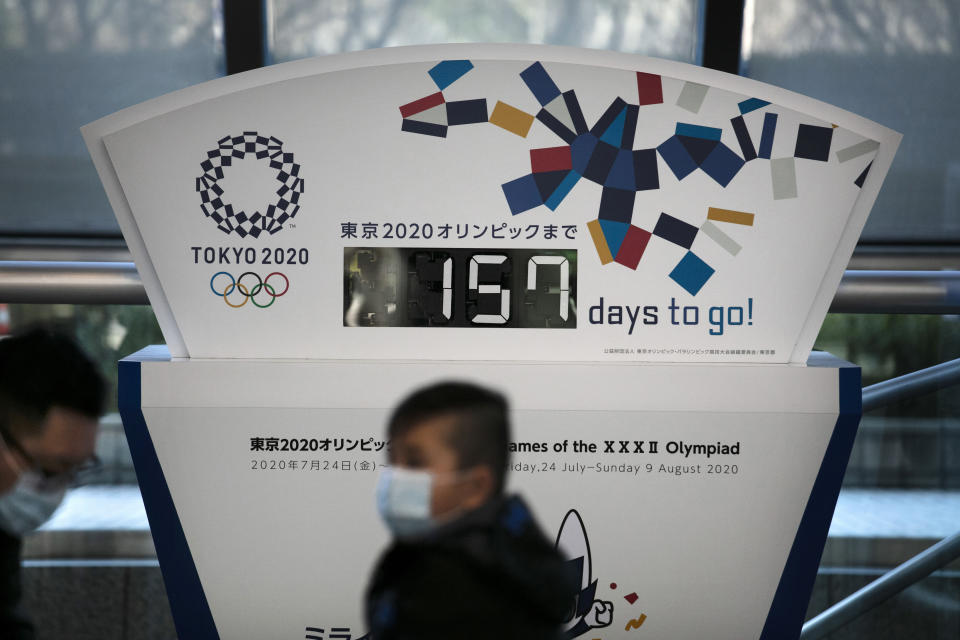 FILE - In this Tuesday, Feb. 18, 2020, file photo, people wearing masks sit in front of a countdown clock for the Tokyo 2020 Olympics in Tokyo. The Tokyo Olympics open in exactly five months on July 24. But the fast-spreading coronavirus from China is making Tokyo organizers very anxious. Three deaths have been reported in Japan with more than 700 cases, more than 600 from a cruise ship that docked in Japan. (AP Photo/Jae C. Hong, File)