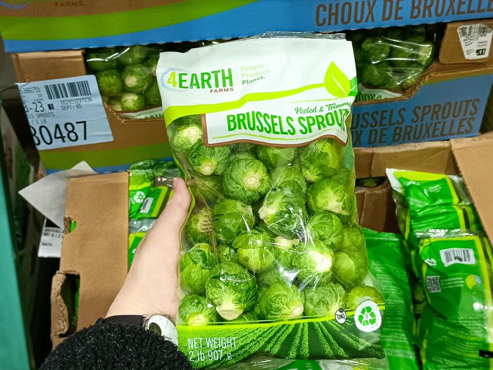 The writer holds a package of Brussels sprouts