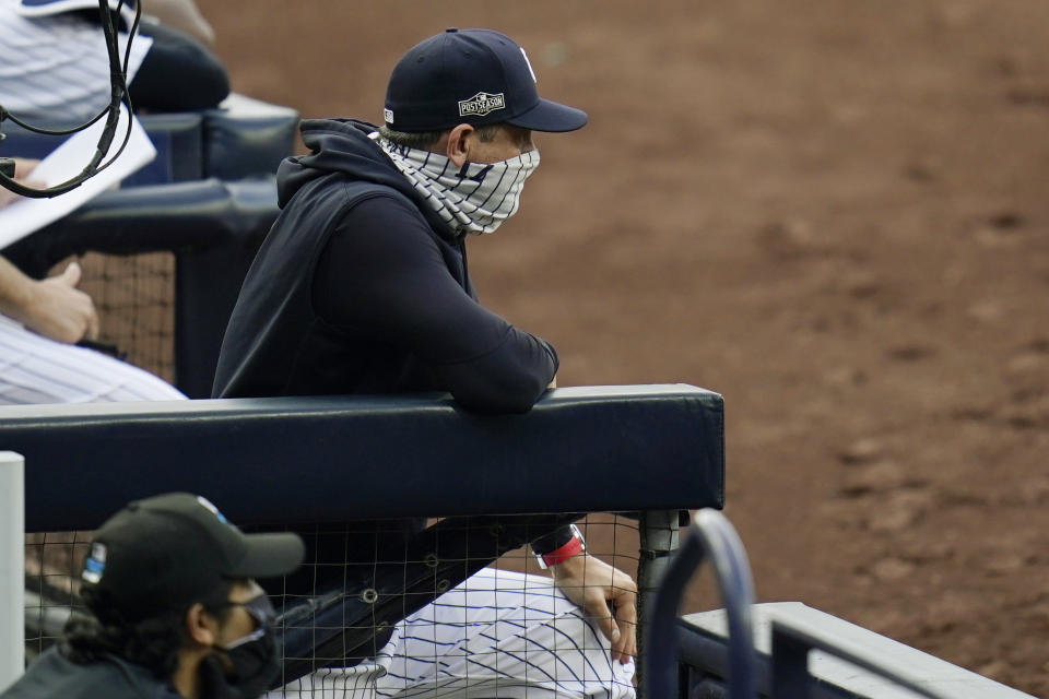 New York Yankees manager Aaron Boone wears a mask as he stands in the dugout during the third inning in Game 4 of a baseball American League Division Series against the Tampa Bay Rays, Thursday, Oct. 8, 2020, in San Diego. (AP Photo/Gregory Bull)